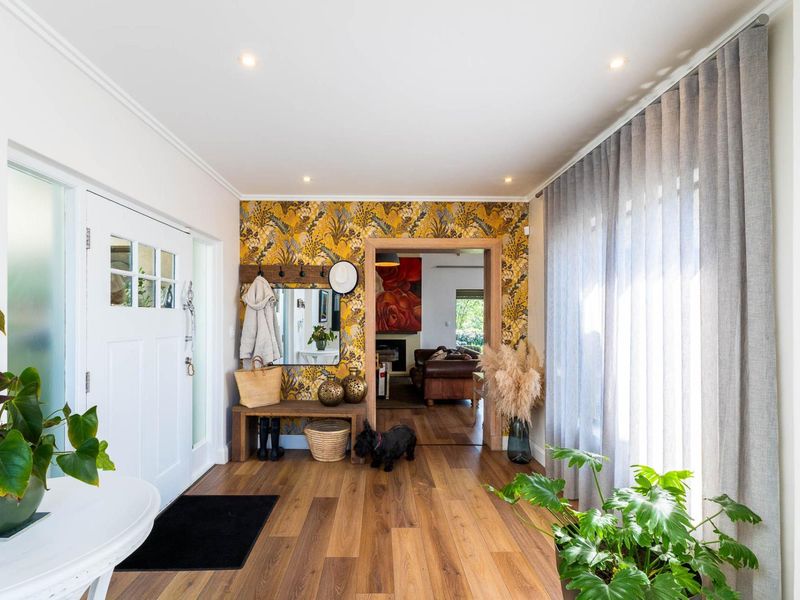 Bright and welcoming entrance hall featuring timber laminate flooring, recessed downlighting, and a decorative feature wall leading into the main living area.