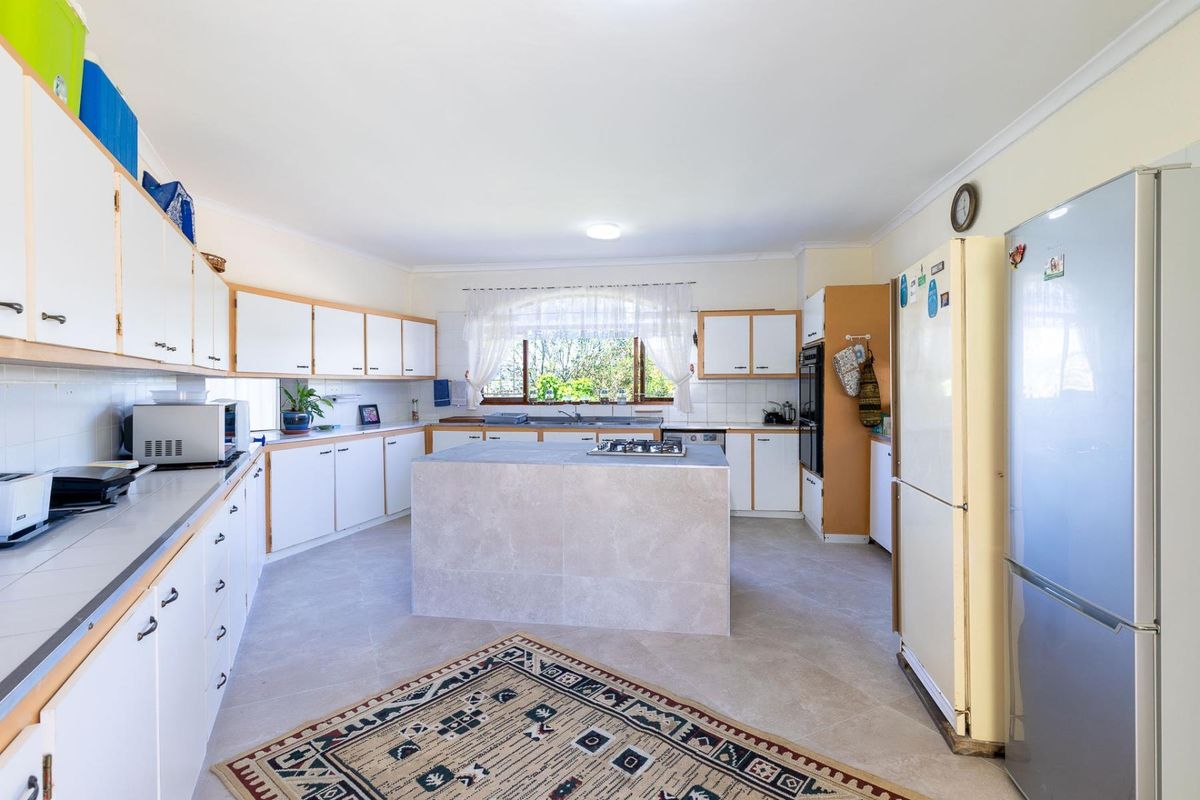 Spacious kitchen featuring a central island with a built-in cooktop, ample cabinetry, and a functional layout with a double sink.