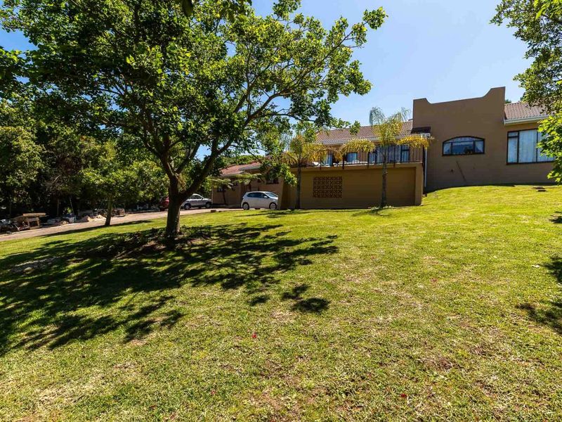 A spacious rear garden featuring a raised patio area with a wrought iron balustrade and decorative breeze block wall, set against the house exterior.