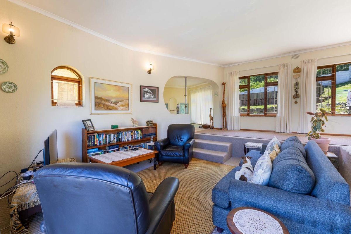 A spacious sunken living room featuring arched architectural detailing, carpeted flooring, and large windows that provide natural light and garden views.