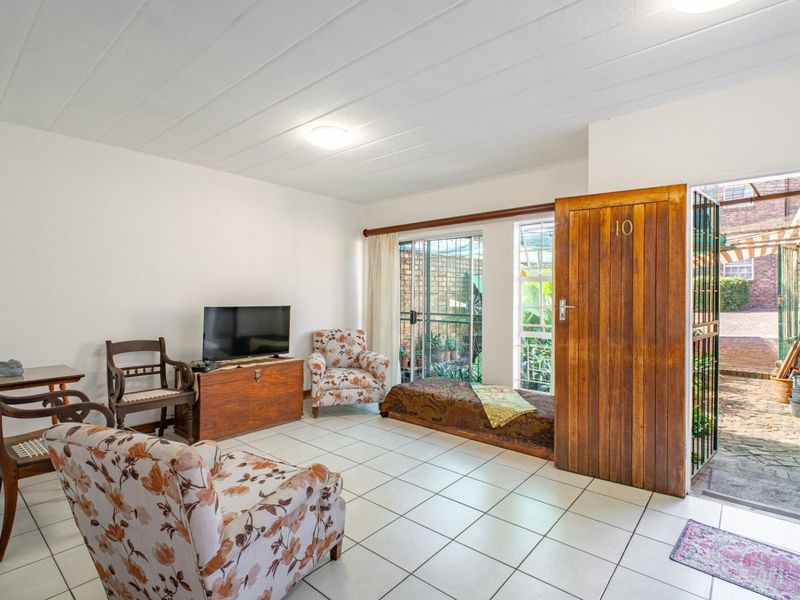 A living area featuring tiled flooring and direct access to an outdoor patio through a sliding glass door and security gate.