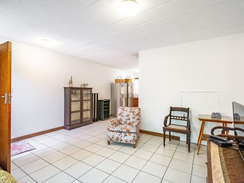 A spacious living area featuring neutral tiled flooring and simple ceiling lighting, offering a blank canvas for modern interior design updates.