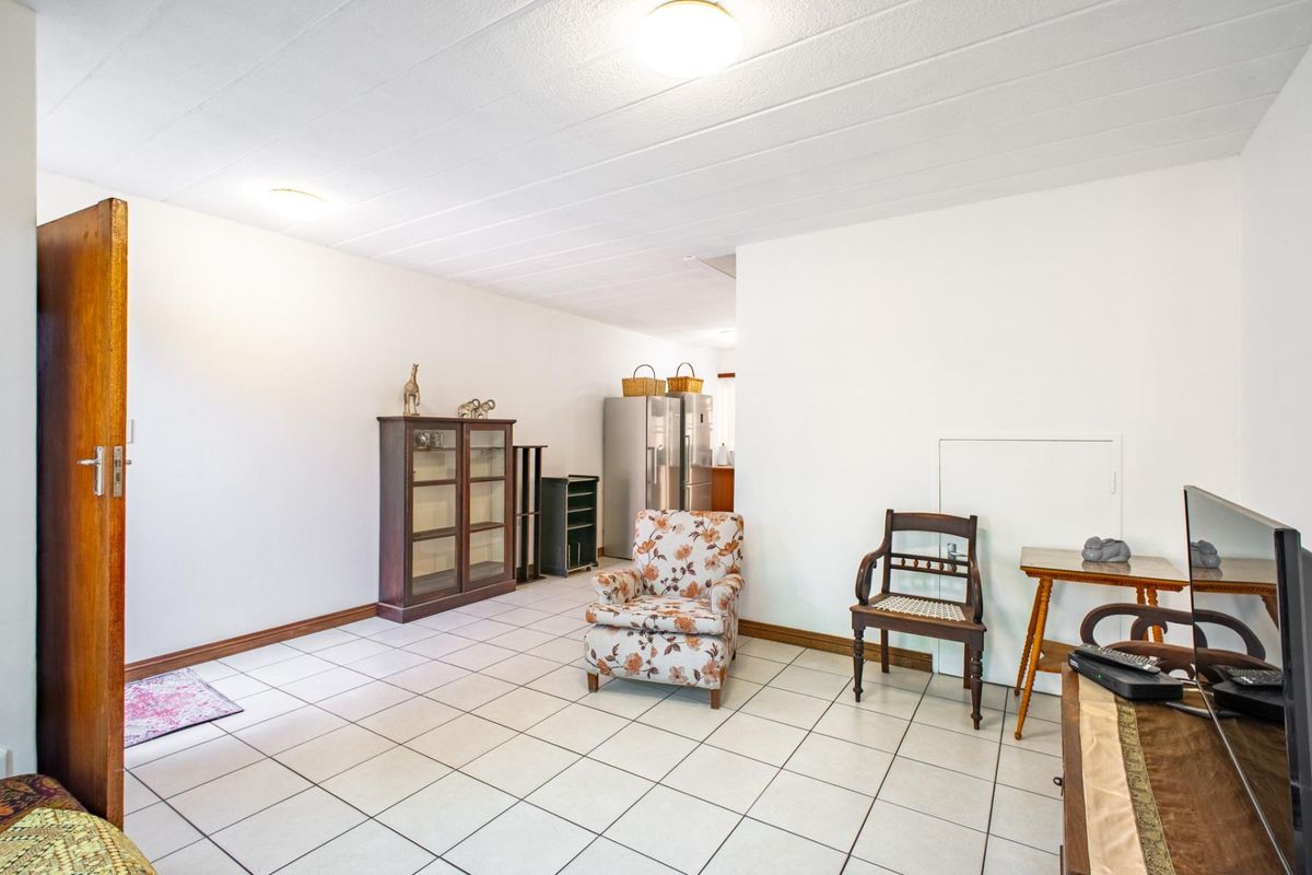 A spacious living area featuring neutral tiled flooring and simple ceiling lighting, offering a blank canvas for modern interior design updates.