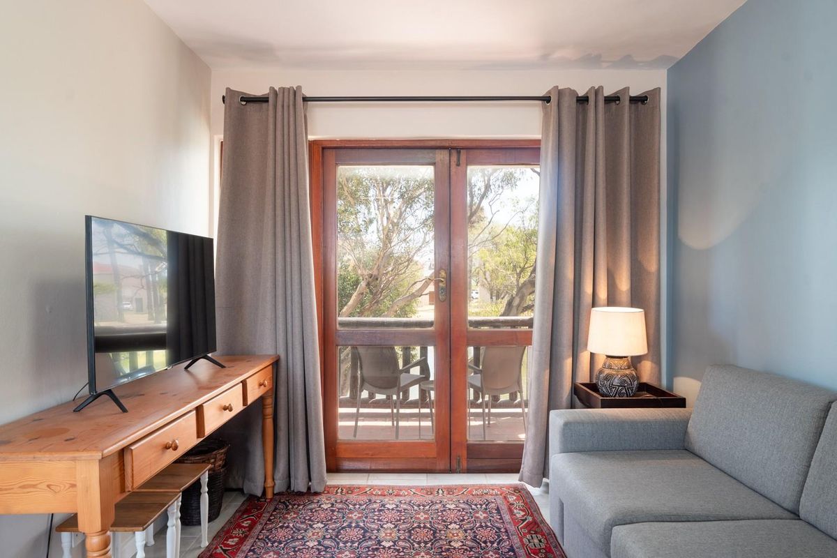 A cozy living room featuring timber-framed glass doors that open onto a balcony, providing natural light and outdoor access.