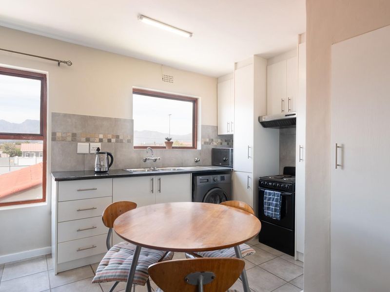 Functional kitchen featuring built-in cabinetry, laminate countertops, tiled backsplash, and integrated appliances, offering a practical layout with natural light.