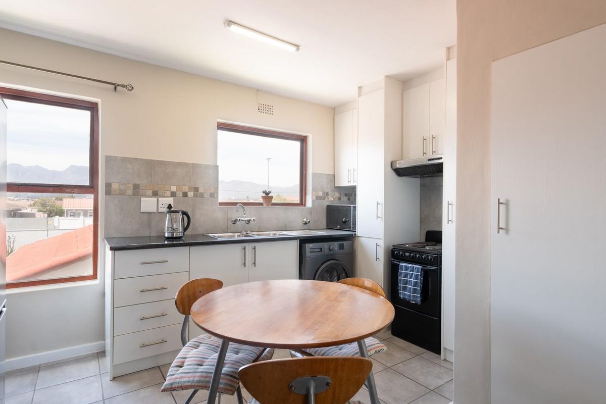 Functional kitchen featuring built-in cabinetry, laminate countertops, tiled backsplash, and integrated appliances, offering a practical layout with natural light.