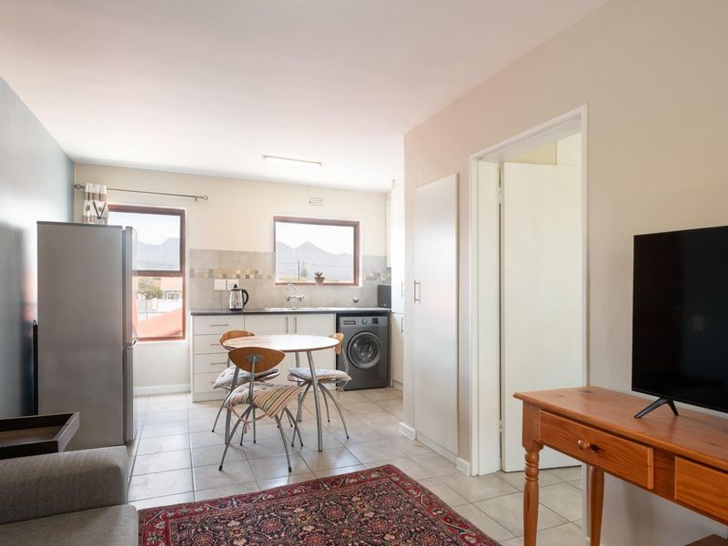Open-plan living area featuring a functional kitchen with tiled flooring, built-in cabinetry, and a dedicated laundry connection, creating a versatile and practical living space.