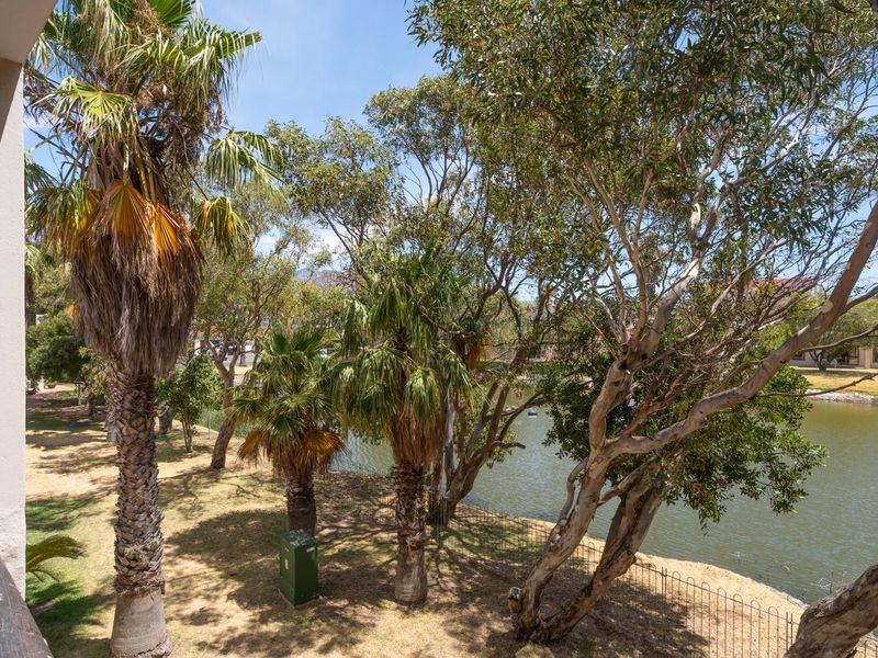 A scenic view overlooking a tranquil pond surrounded by mature trees and landscaped garden areas, providing a peaceful outdoor outlook.