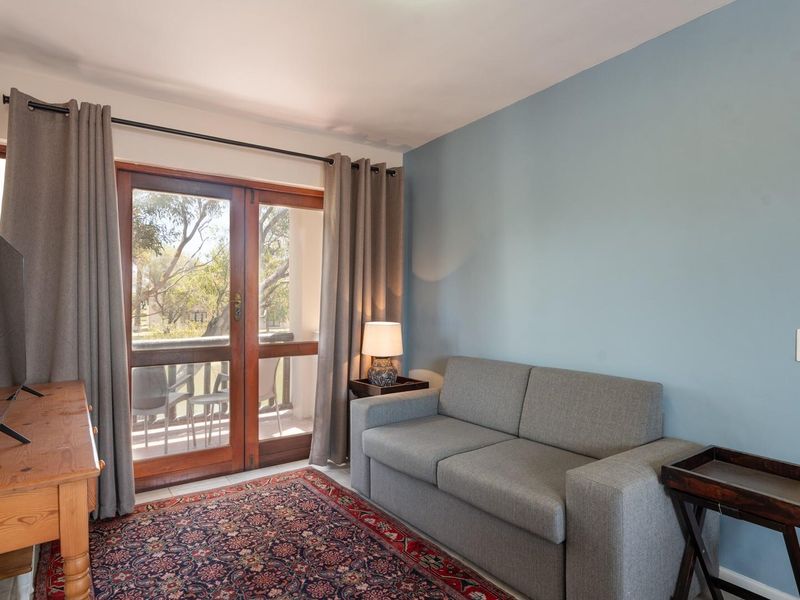 A cozy living room featuring tiled flooring and timber-framed glass doors that provide access to an outdoor balcony area.