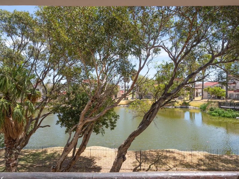 A scenic view overlooking a tranquil pond and landscaped grounds, framed from a private balcony.