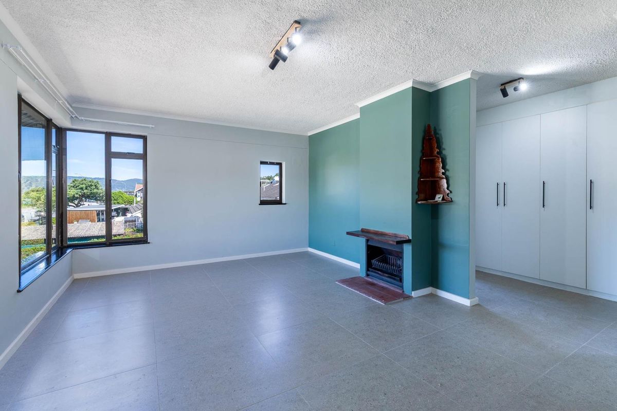 Spacious living area featuring tiled flooring, a built-in fireplace, ample built-in cupboard storage, and large windows providing natural light.