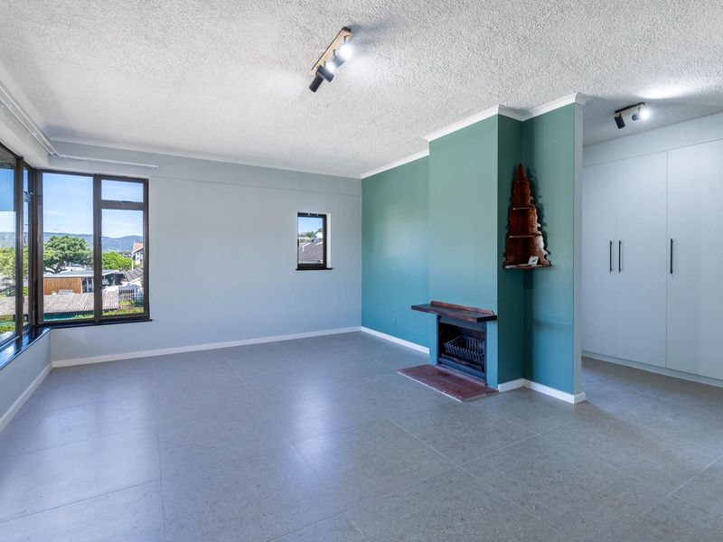 Spacious living area featuring tiled flooring, a built-in fireplace, ample built-in cupboard storage, and large windows providing natural light.