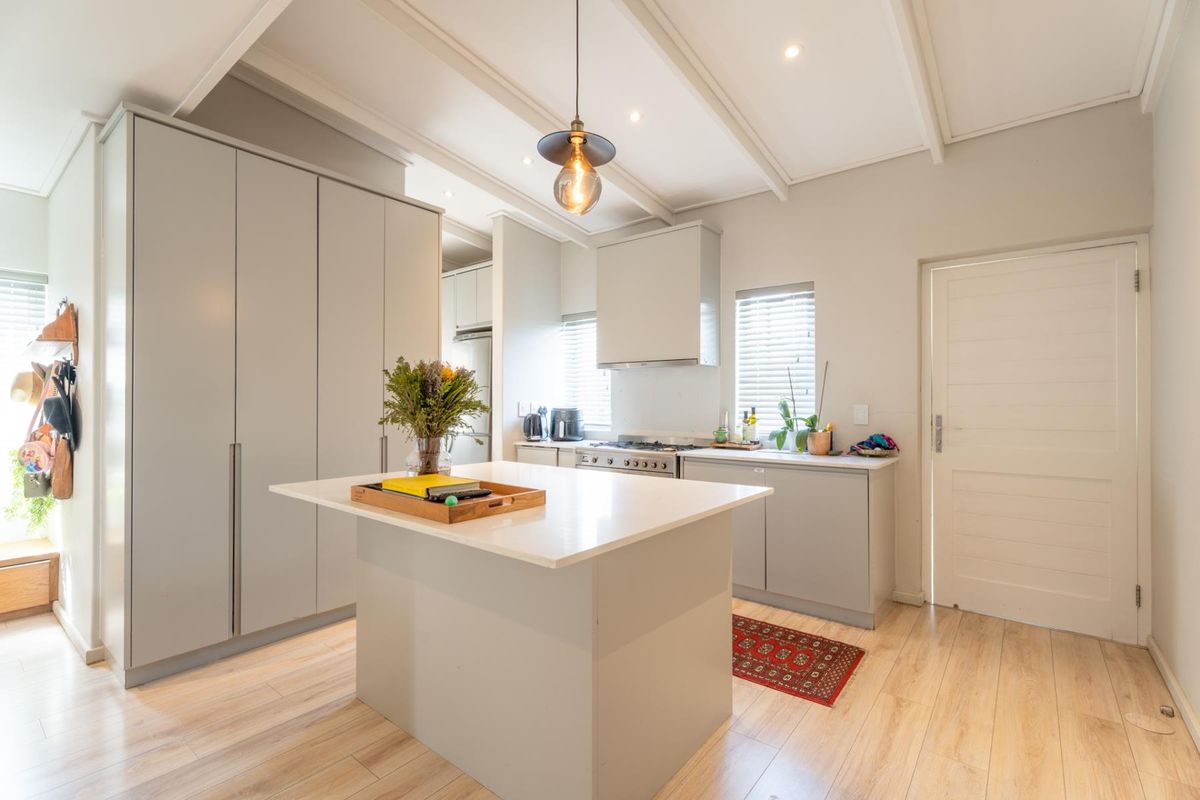 Modern kitchen featuring a central island with quartz countertops, sleek built-in cabinetry, gas stove, and high-quality laminate flooring under a bright, contemporary ceiling.