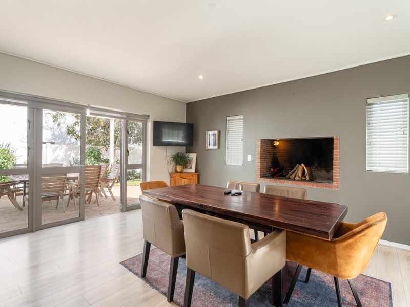 Spacious dining area featuring a built-in fireplace, modern laminate flooring, and large sliding glass doors providing seamless access to the outdoor patio.