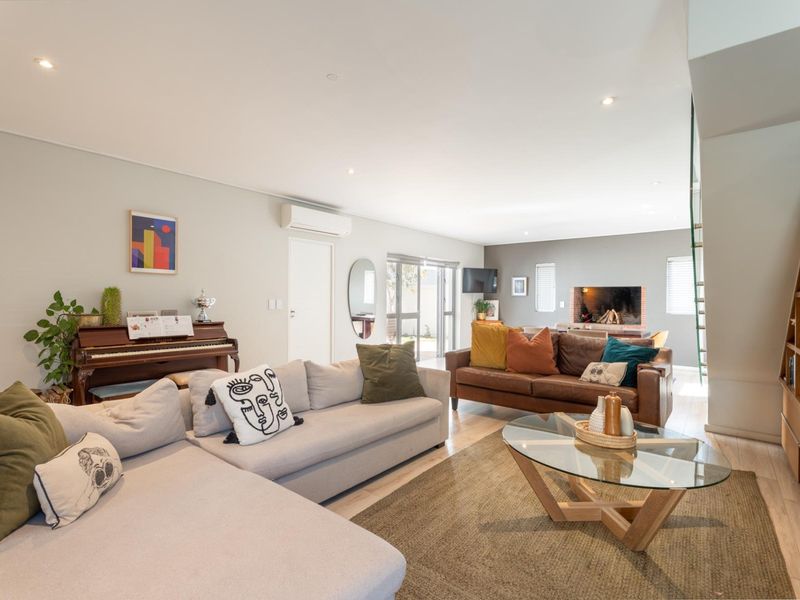 Spacious living room featuring a built-in fireplace, integrated shelving, split-system air conditioning, and recessed downlights, creating a comfortable and well-lit atmosphere.