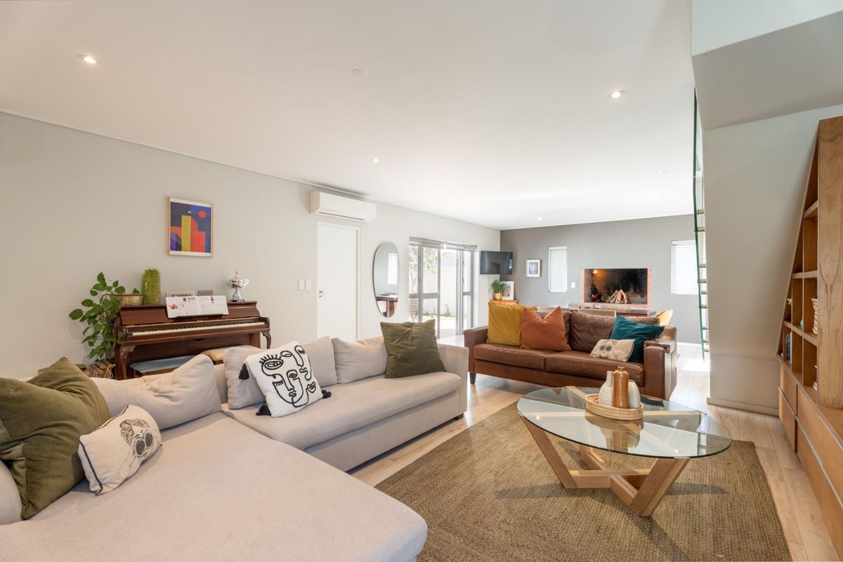 Spacious living room featuring a built-in fireplace, integrated shelving, split-system air conditioning, and recessed downlights, creating a comfortable and well-lit atmosphere.