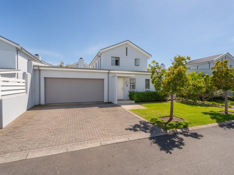 Front exterior view of a townhouse featuring a paved driveway, single garage, and a well-maintained front lawn.
