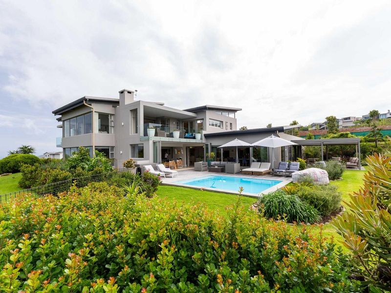 Spacious rear exterior featuring a modern multi-level home, swimming pool, timber decking, and a well-maintained landscaped garden.