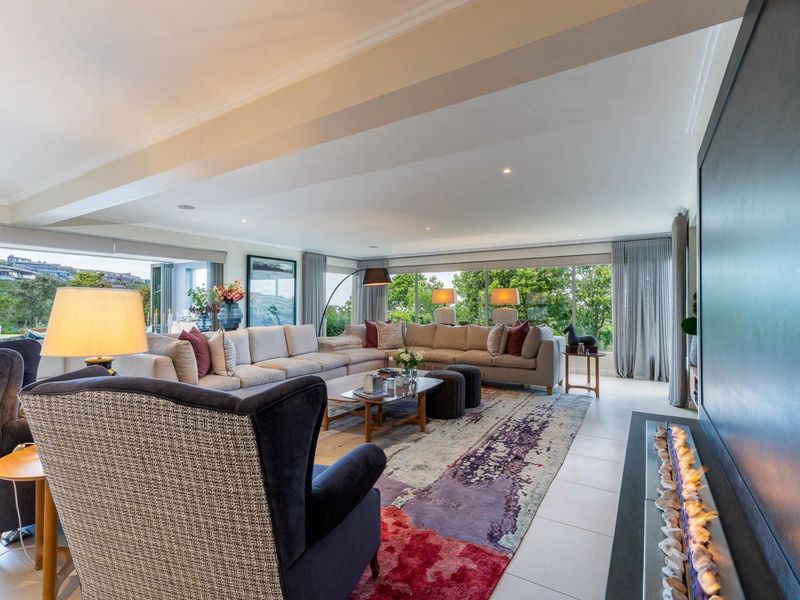 Spacious, modern living room featuring a sleek built-in fireplace, large sliding glass doors with garden views, and high-quality tiled flooring.