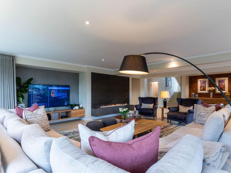 Spacious living room featuring a modern built-in fireplace, exposed brick accents, recessed lighting, and a sleek media unit, creating a warm and inviting atmosphere.