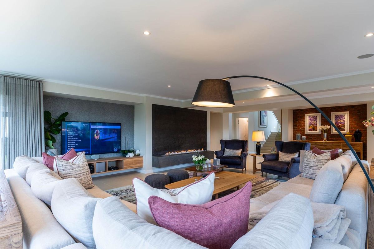 Spacious living room featuring a modern built-in fireplace, exposed brick accents, recessed lighting, and a sleek media unit, creating a warm and inviting atmosphere.