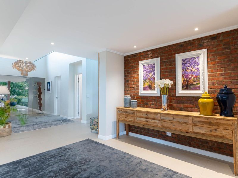 Spacious entrance hall featuring a striking exposed brick feature wall, modern tiled flooring, and recessed downlighting, creating a warm and inviting atmosphere.