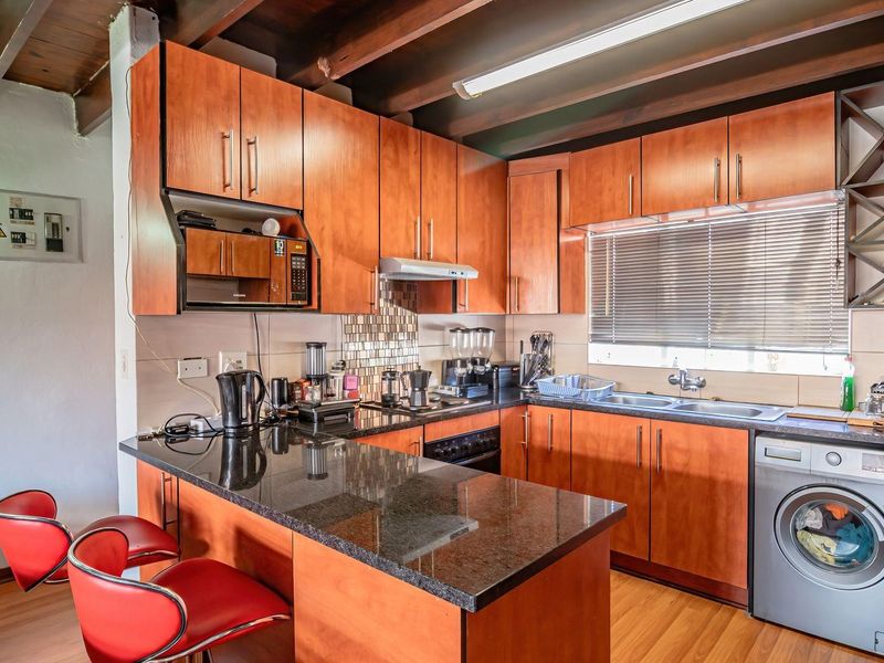 Functional kitchen featuring warm-toned cabinetry, granite countertops, integrated oven, and exposed timber ceiling beams, providing a practical and well-utilized cooking space.