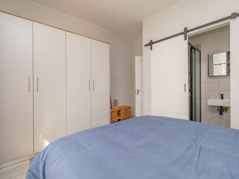 A well-maintained bedroom featuring ample built-in cupboard storage and a modern sliding barn door providing access to an en-suite bathroom.