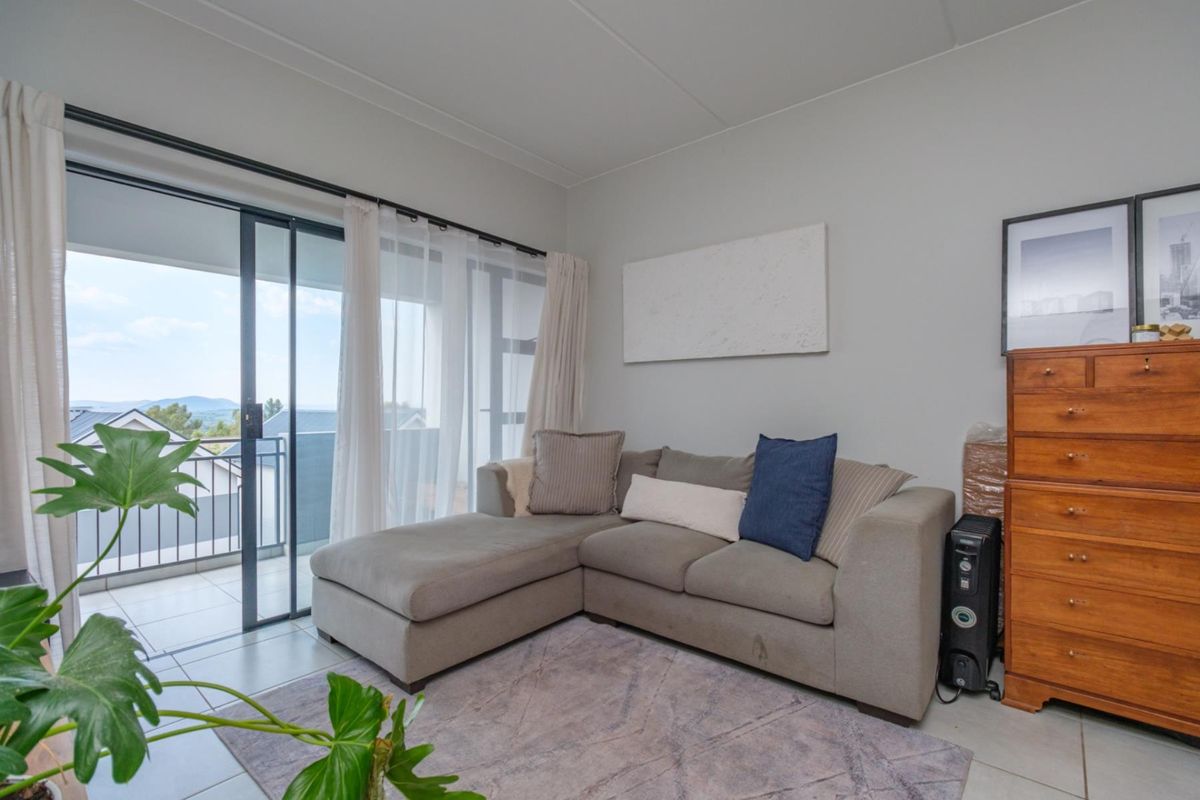 A bright living room featuring tiled flooring and a large sliding glass door that provides direct access to an outdoor balcony.