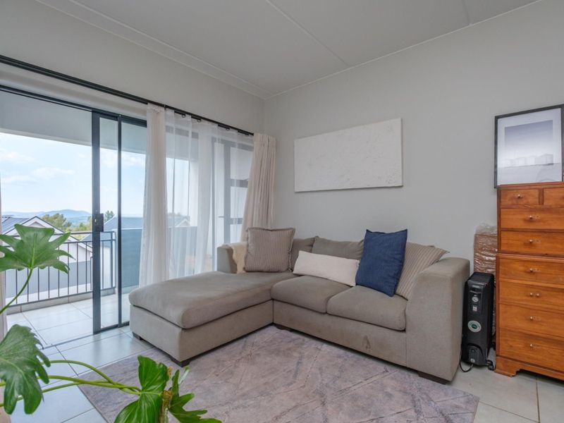A bright living room featuring tiled flooring and a large sliding glass door that provides direct access to an outdoor balcony.