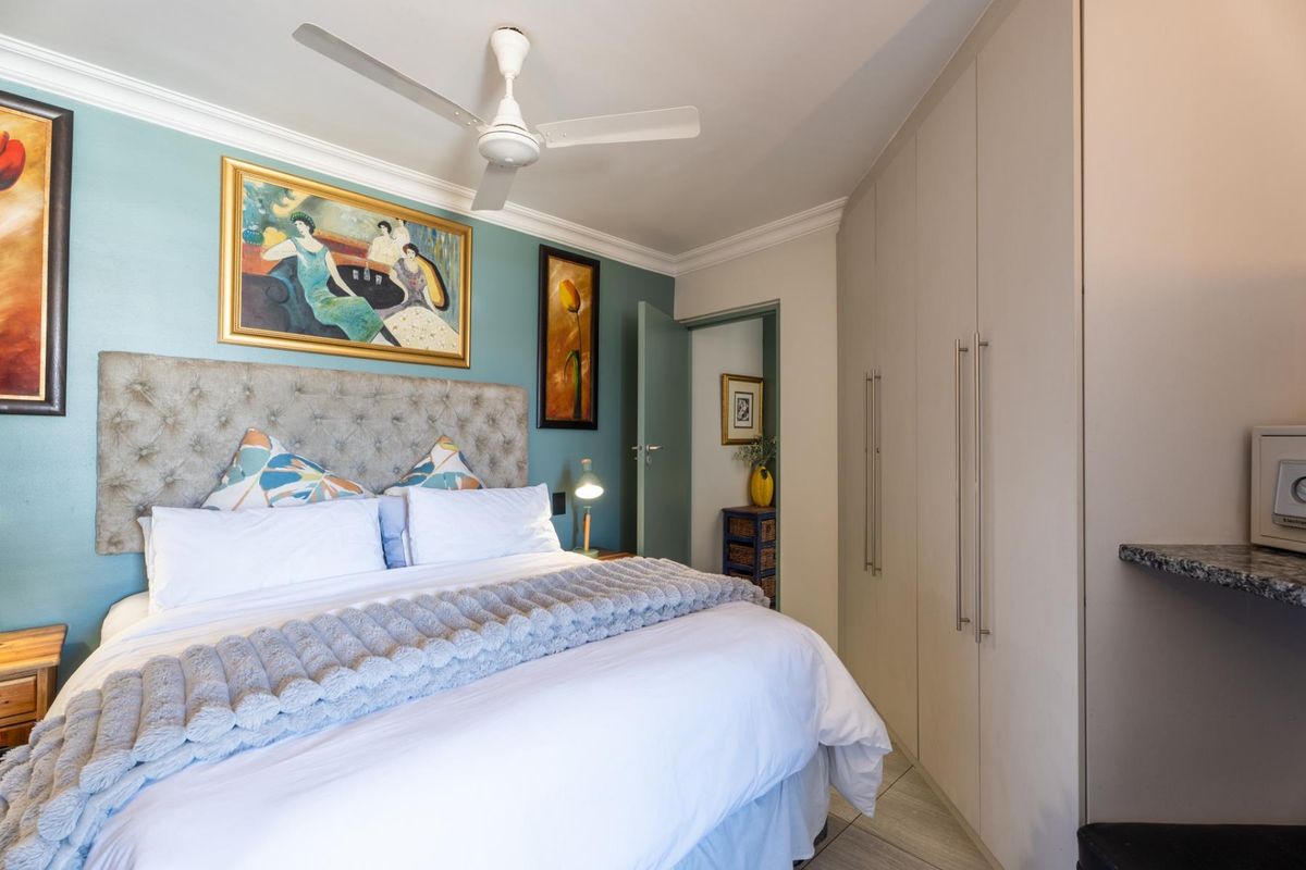 A well-maintained bedroom featuring built-in cupboards, a ceiling fan, and tiled flooring, offering a comfortable and functional living space.