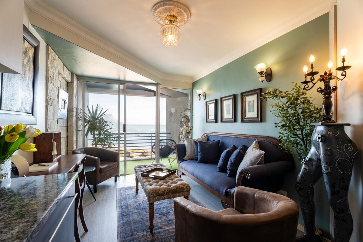 A well-appointed living room featuring a stone accent wall, elegant ceiling rose, and sliding glass doors that open to a balcony with ocean views.