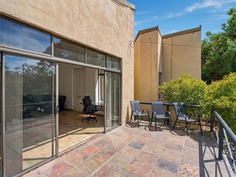 A spacious outdoor patio featuring tiled flooring, metal railings, and large sliding glass doors providing seamless access to the interior living space.