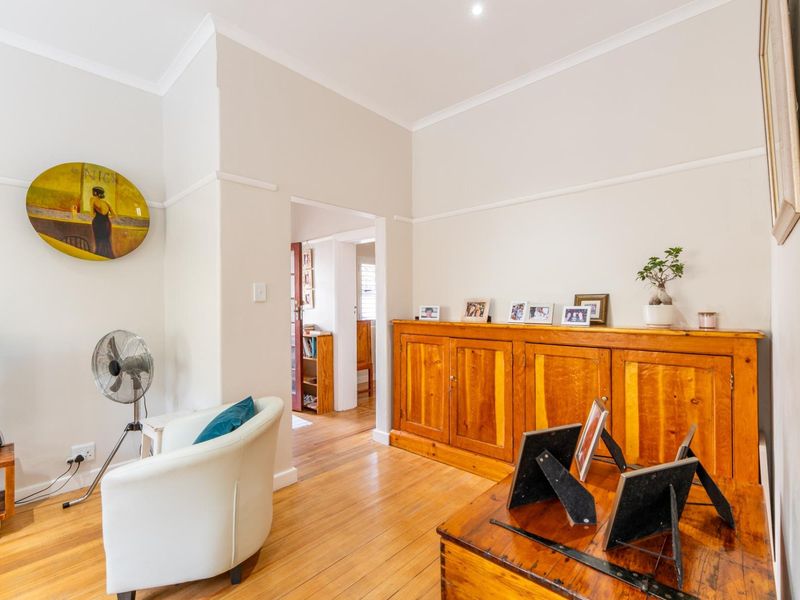 A well-maintained living room featuring polished hardwood flooring, classic picture rails, coved cornicing, and integrated wooden cabinetry.