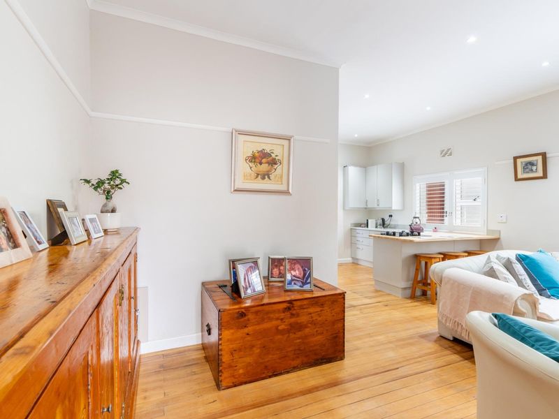 An open-plan living and kitchen area featuring warm hardwood flooring, recessed lighting, and a functional kitchen island with built-in cabinetry.