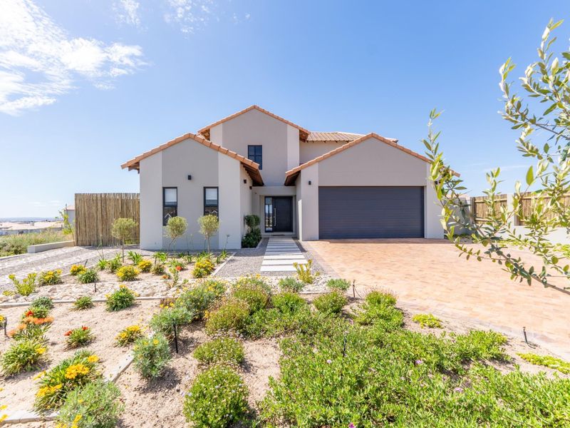 A modern double-story home featuring a tiled roof, paved driveway, double garage, and a well-maintained landscaped front garden.