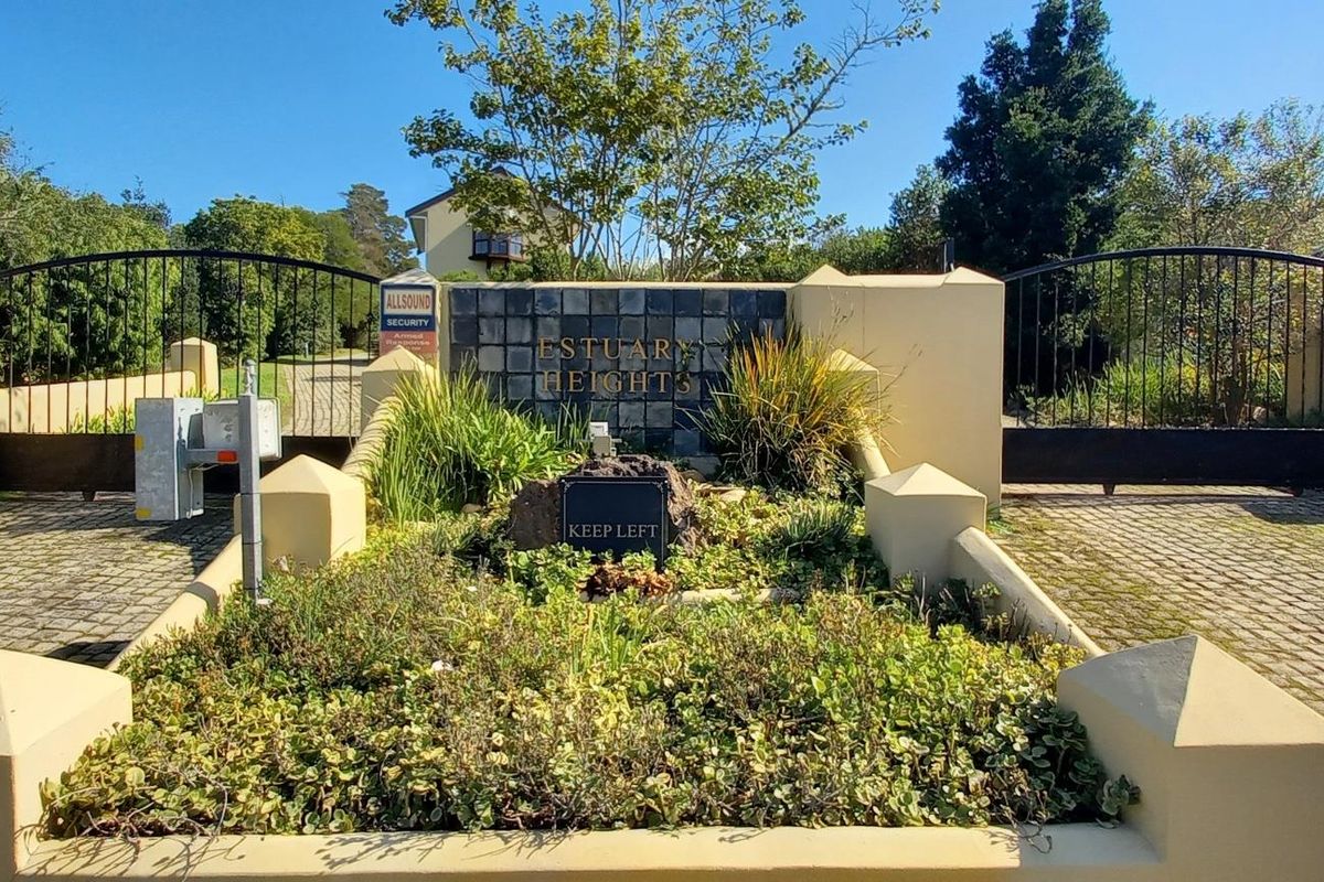 The entrance to Estuary Heights featuring a secure gated access point with cobblestone driveway and established landscaped garden beds.