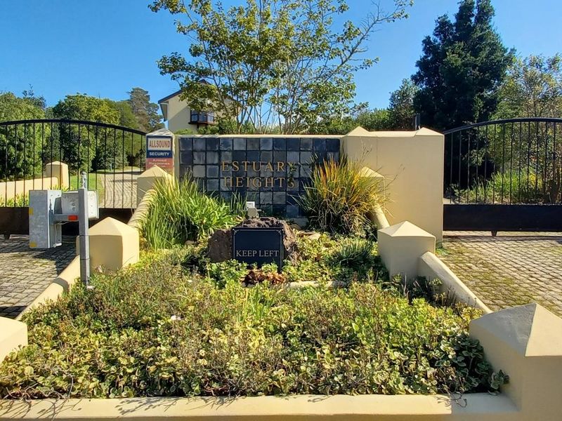 The entrance to Estuary Heights featuring a secure gated access point with cobblestone driveway and established landscaped garden beds.