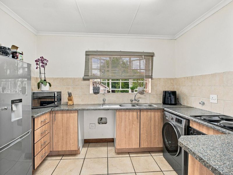 Functional kitchen featuring laminate cabinetry, granite countertops, double basin sink, and ceramic tile flooring with space for under-counter appliances.
