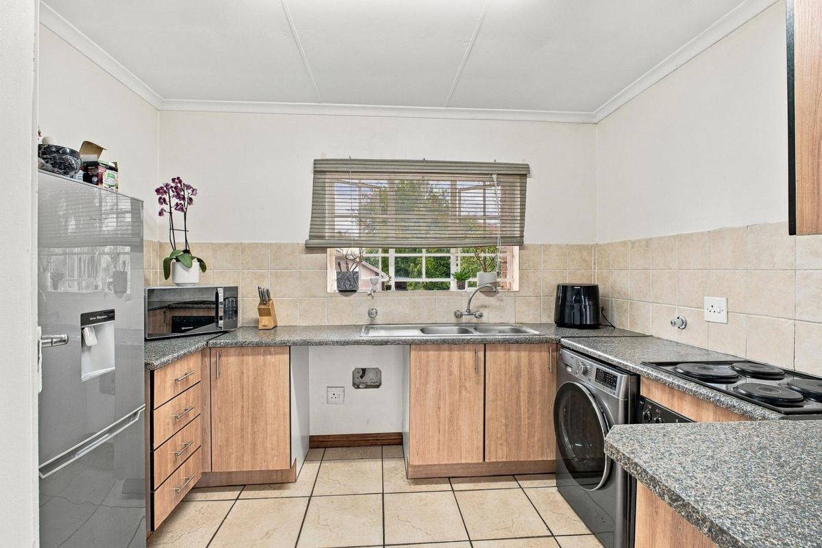 Functional kitchen featuring laminate cabinetry, granite countertops, double basin sink, and ceramic tile flooring with space for under-counter appliances.