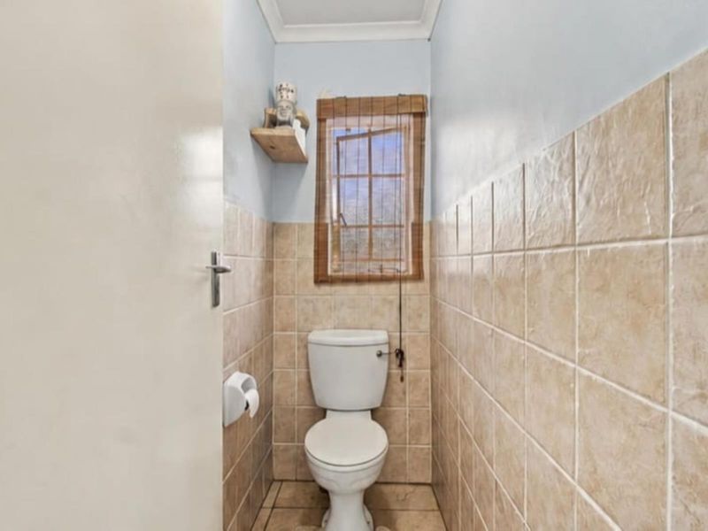 A compact, functional guest bathroom featuring neutral ceramic wall and floor tiling and a standard toilet suite.