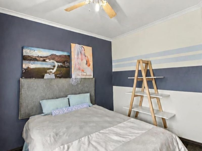 A bedroom featuring a ceiling fan and decorative wall paint, providing a functional space with standard architectural finishes.