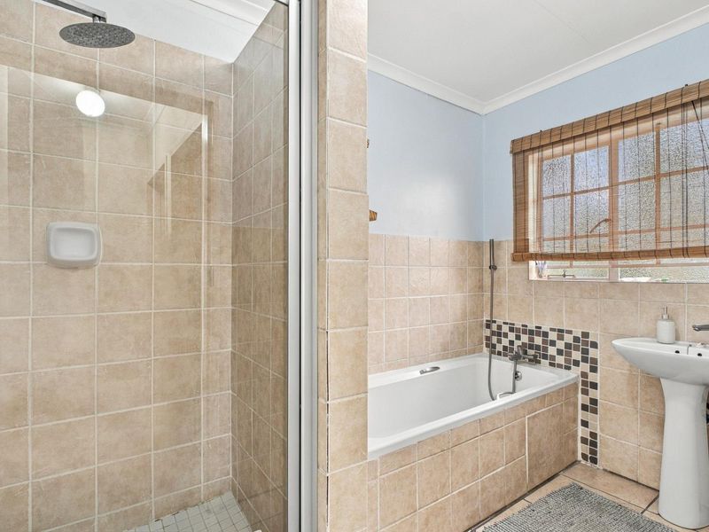 A functional bathroom featuring a separate shower enclosure, a built-in bathtub with tiled surround, and a pedestal sink.