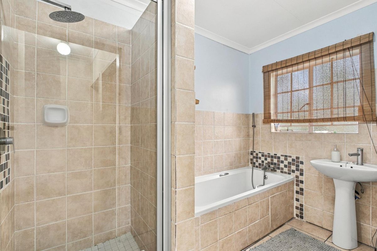 A functional bathroom featuring a separate shower enclosure, a built-in bathtub with tiled surround, and a pedestal sink.
