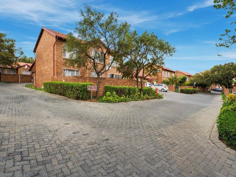 A view of the complex street and driveway area featuring brick-paved roads and established brick apartment buildings with tiled roofs.