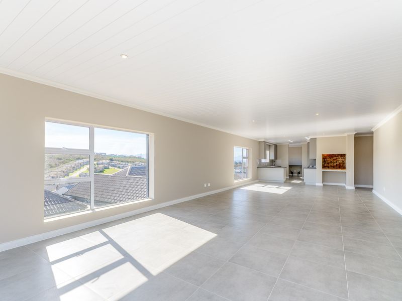 Spacious open-plan living area featuring neutral tiled floors, a modern tongue and groove ceiling, and an integrated kitchen with a built-in indoor braai.