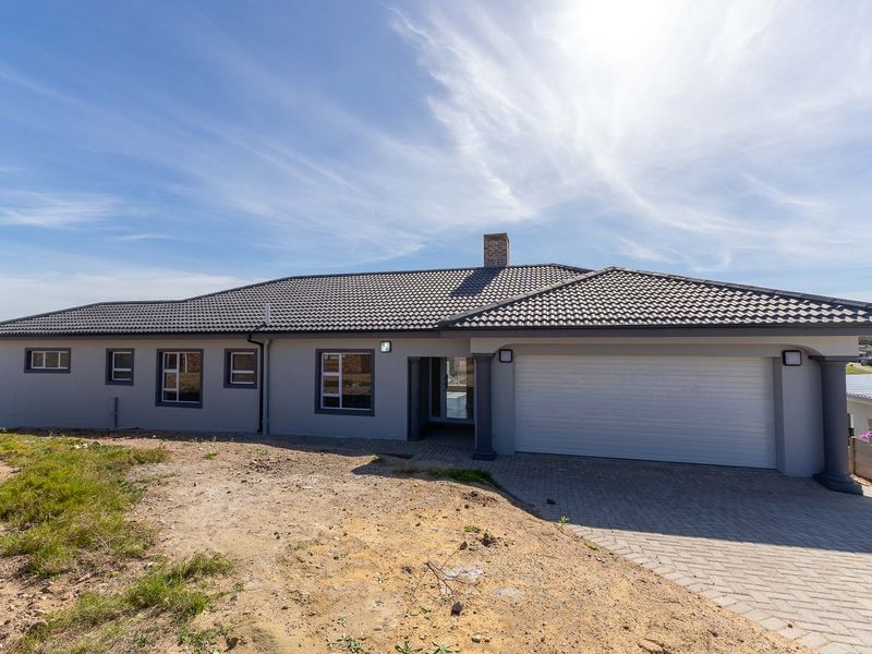 Modern single-story residential home featuring a tiled roof, paved driveway, and integrated garage, set on a plot with unfinished landscaping.