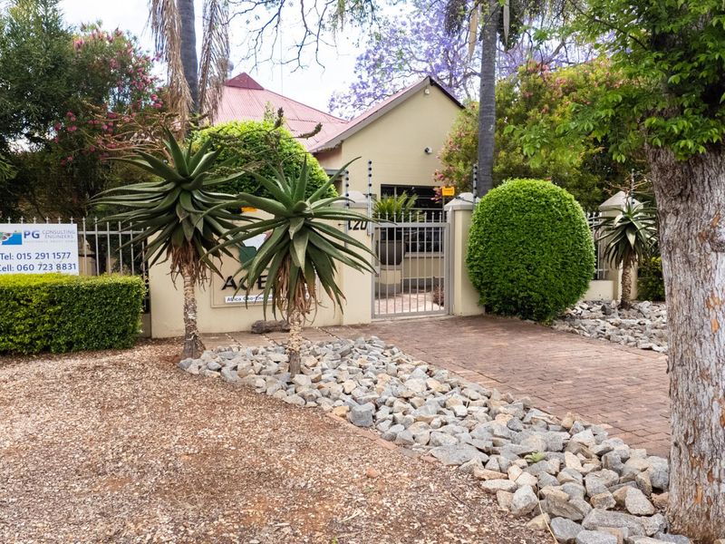 Front exterior view of the office property featuring a paved driveway, secure metal gate, and perimeter electric fencing.