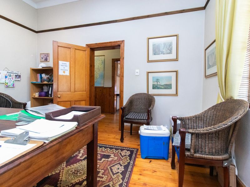 A functional office space featuring warm timber flooring, classic wooden door frames, and natural light through window blinds.