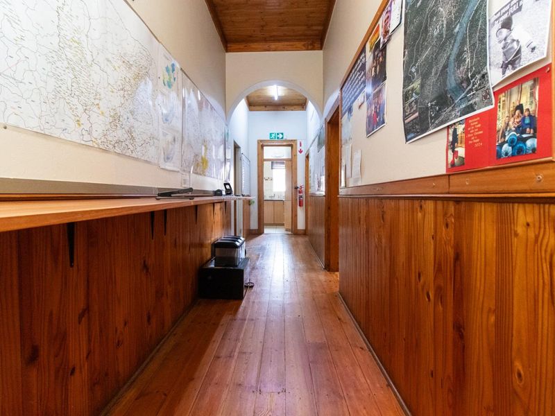 A long office hallway featuring timber wall paneling, wooden flooring, and a timber-clad ceiling with an arched transition.